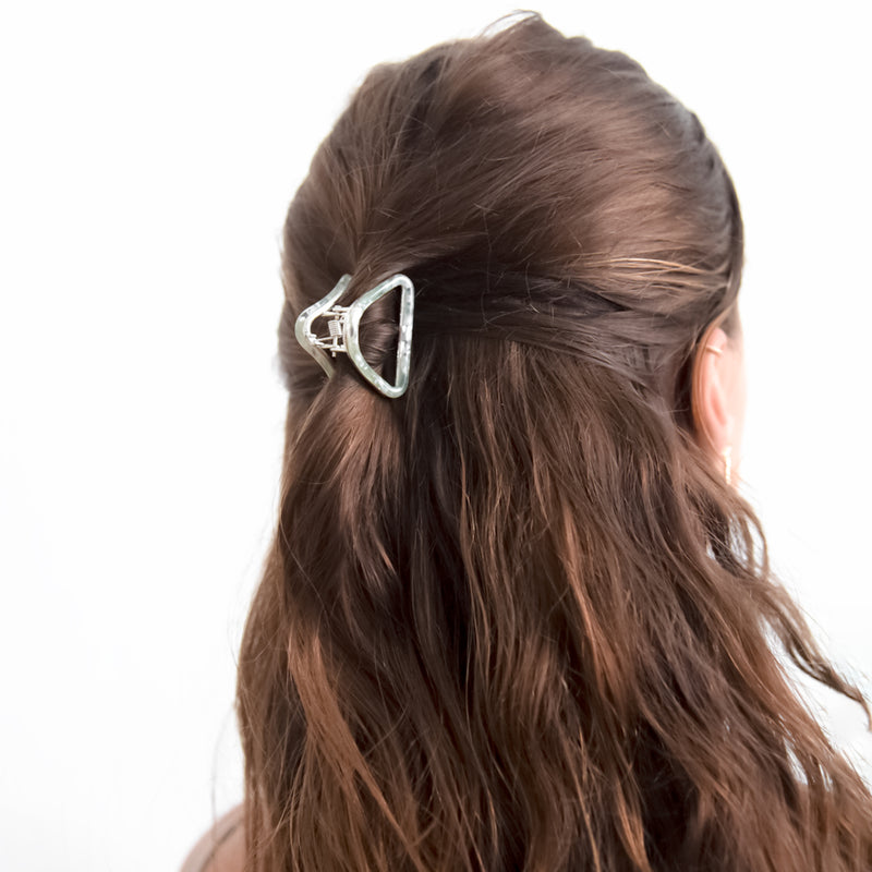 Woman styling hair with sage French style triangle hair claw clip, perfect for all hair types